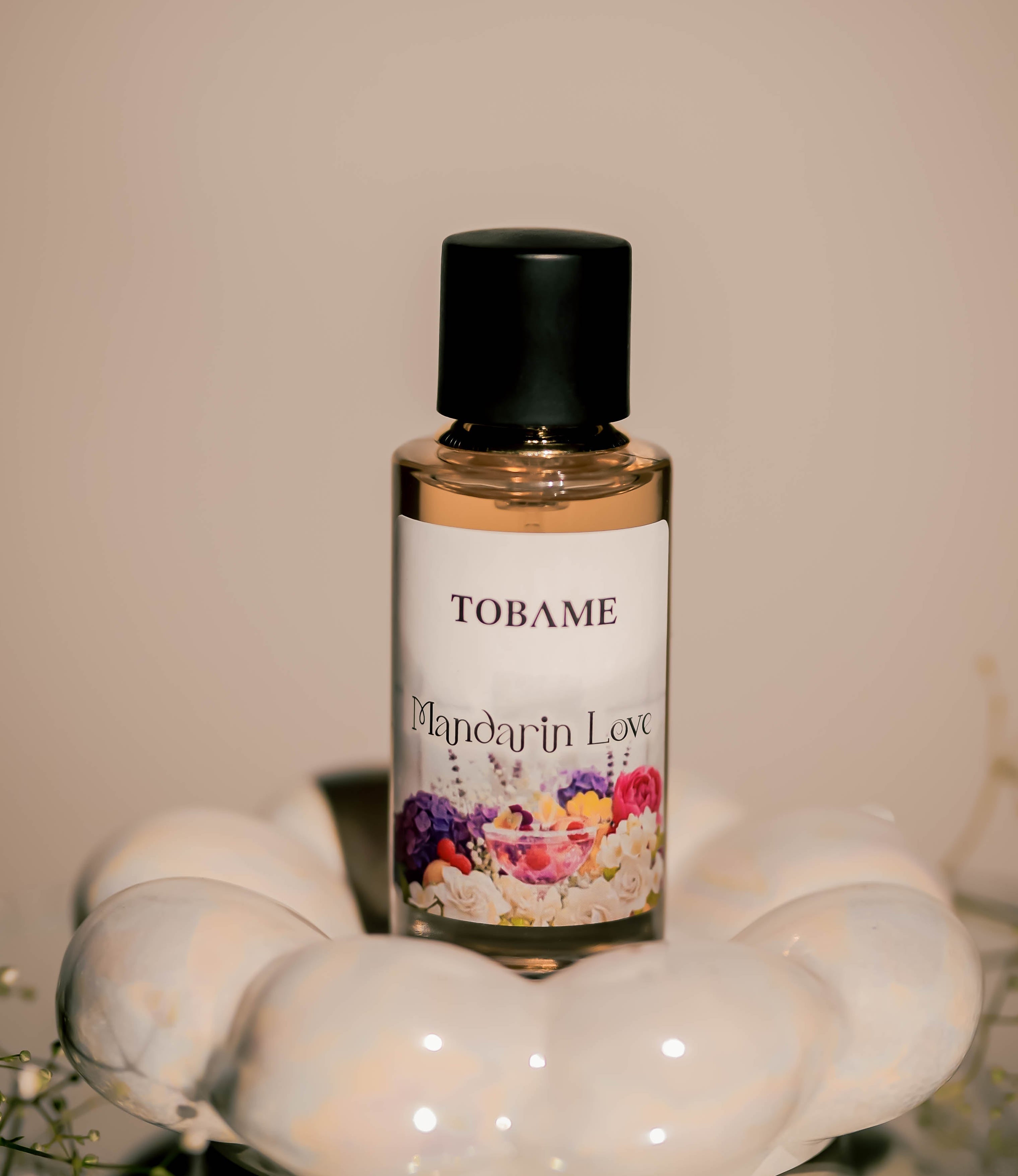 Tobame Mandarin Love perfume bottle on a decorative stand with a neutral background